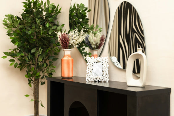 A console table with vases, a plant, and decorative mirrors.